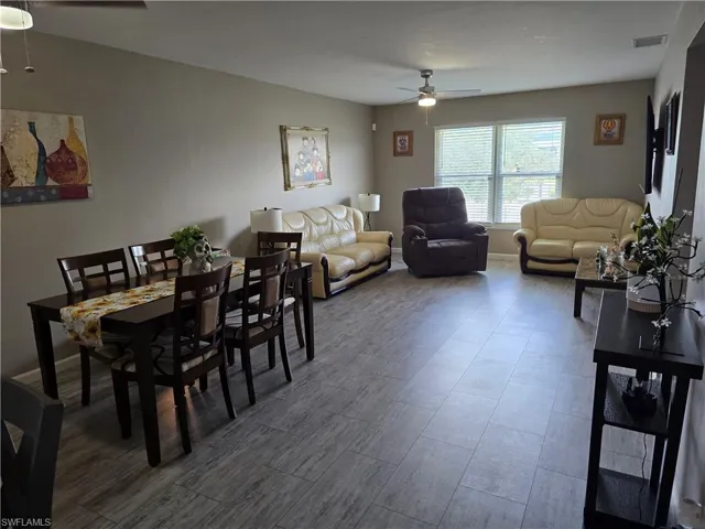 Wood-finish flooring throughout, ceiling fan with integrated lighting, and multiple windows with blinds