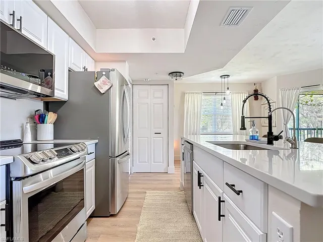 Kitchen with light wood-type flooring, visible vents, light countertops, a sink, and stainless steel appliances