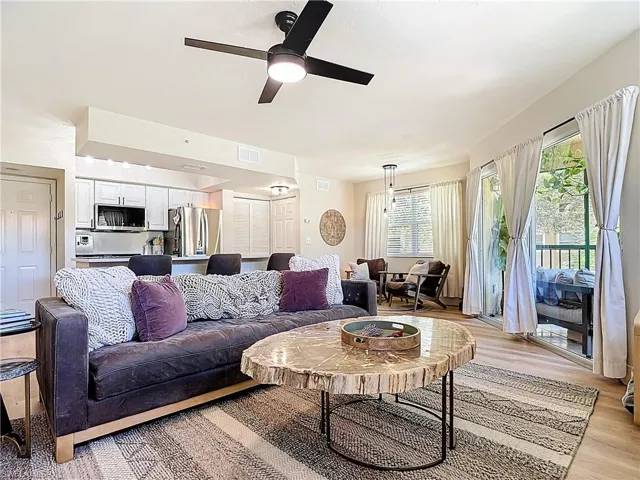 Living room featuring light wood-type flooring, ceiling fan, and visible vents