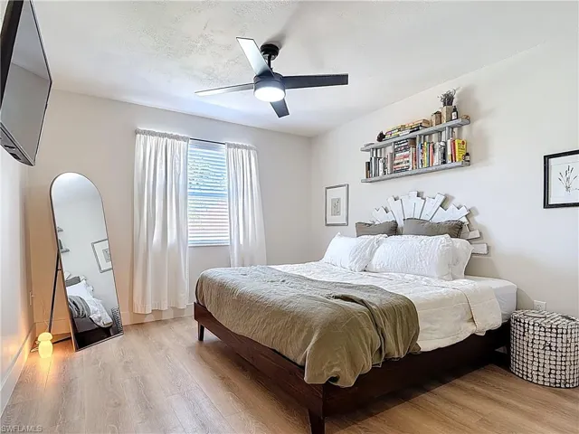 Bedroom featuring a textured ceiling, light wood finished floors, arched walkways, and a ceiling fan