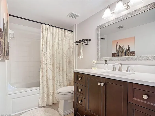 Bathroom with visible vents, toilet, shower / bathtub combination with curtain, and vanity