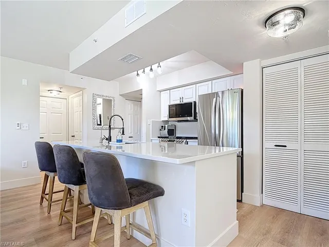 Kitchen featuring visible vents, light wood-style floors, a kitchen bar, and stainless steel appliances