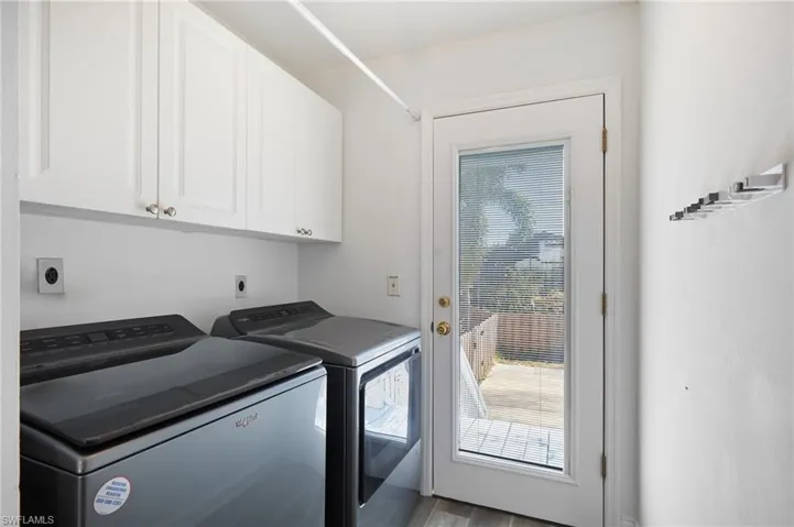Laundry room with washing machine and clothes dryer, cabinet space, and plenty of natural light