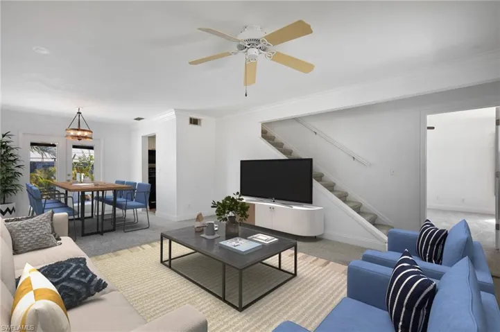 Living room featuring crown molding, light colored carpet, stairs, baseboards, and visible vents