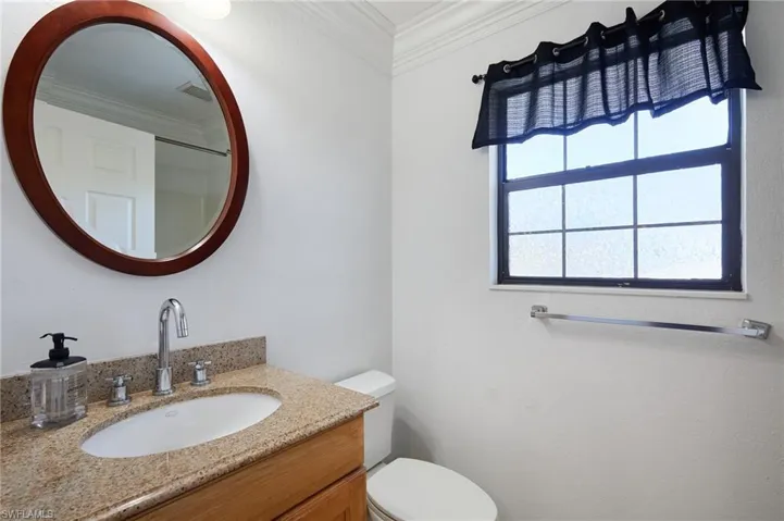 Bathroom with toilet, ornamental molding, vanity, and visible vents