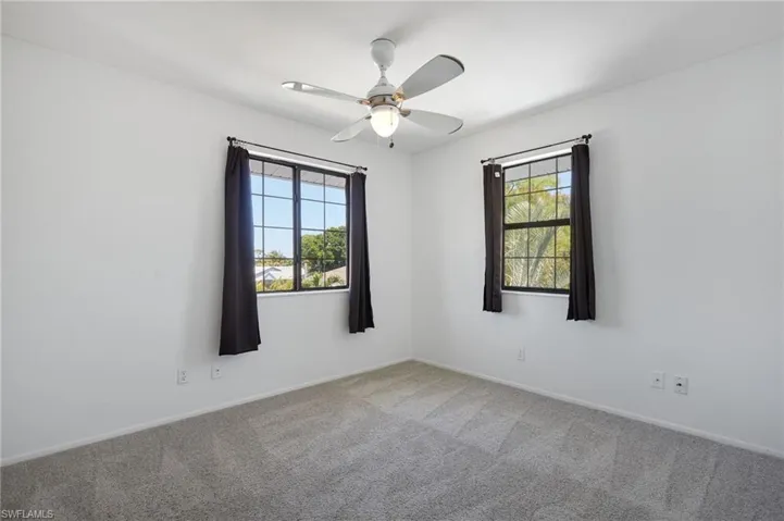 Carpeted empty room featuring a ceiling fan, baseboards, and a healthy amount of sunlight