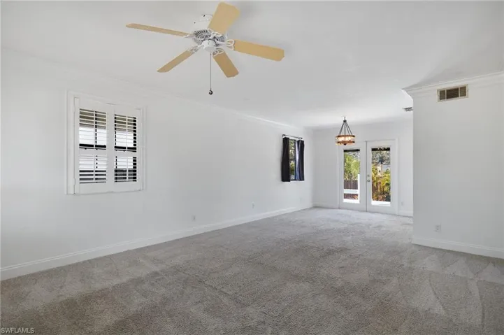 Carpeted spare room featuring visible vents, crown molding, and baseboards