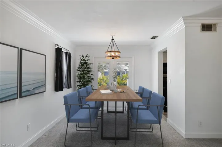 Carpeted dining space featuring an inviting chandelier, ornamental molding, baseboards, and visible vents