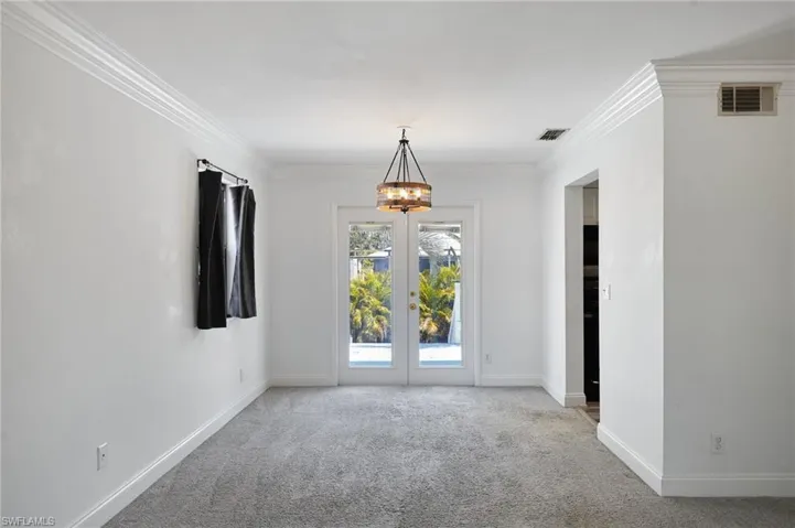 Empty room featuring visible vents, an inviting chandelier, and light colored carpet