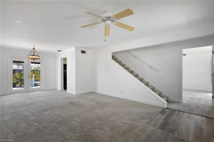 Unfurnished living room with baseboards, ornamental molding, stairs, and visible vents