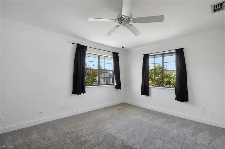 Unfurnished room featuring carpet, visible vents, a wealth of natural light, and crown molding