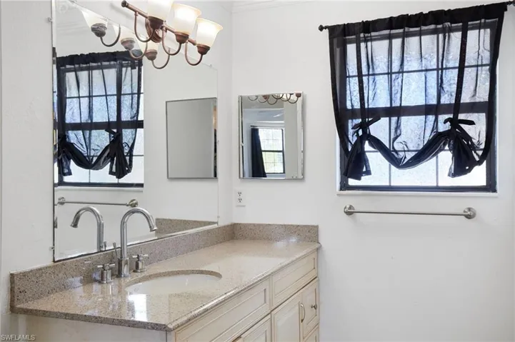 Bathroom featuring ornamental molding, vanity, and a notable chandelier