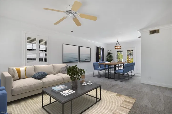 Living area with crown molding, baseboards, light colored carpet, and visible vents