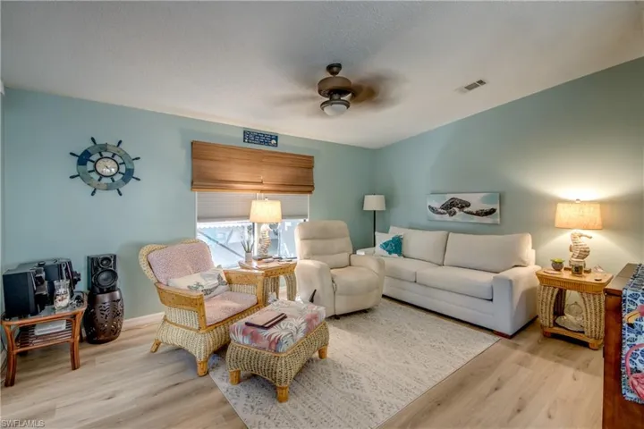 Living room featuring light wood finished floors, a ceiling fan, and a textured ceiling
