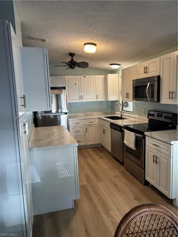 Kitchen with white cabinetry, stainless steel appliances, and marble-finish countertops