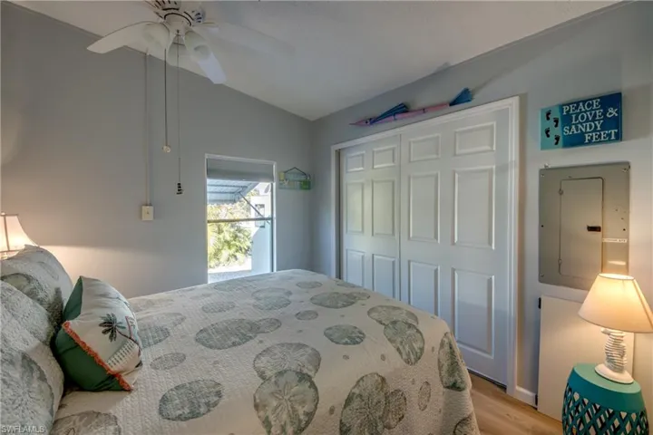 Bedroom with electric panel, light wood-type flooring, a closet, vaulted ceiling, and ceiling fan
