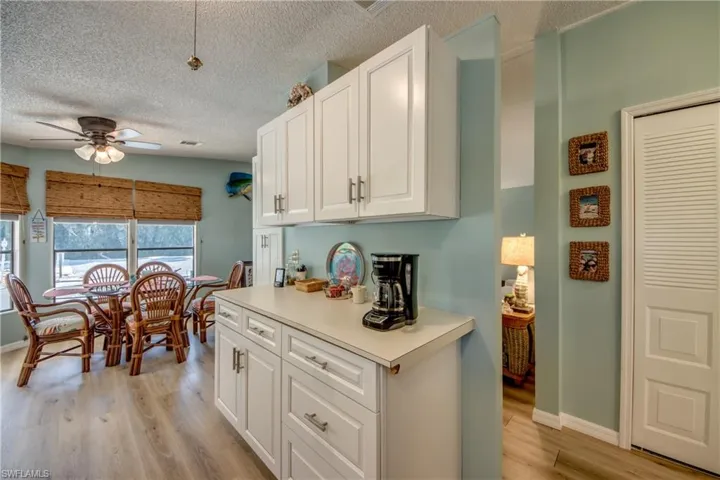 Kitchen with light countertops, white cabinetry, ceiling fan, light wood-style floors, and a textured ceiling