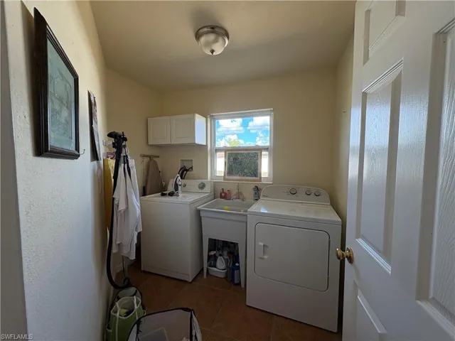Laundry room with dark tile patterned floors, separate washer and dryer, and cabinet space