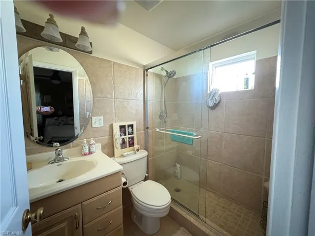 Bathroom with vanity, tile walls, a stall shower, and ensuite bath