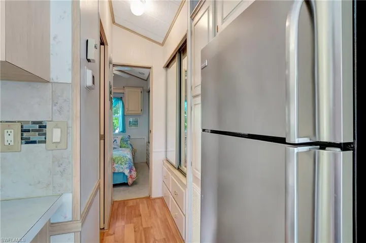 Kitchen with stainless steel fridge, light wood-type flooring, vaulted ceiling, and ornamental molding