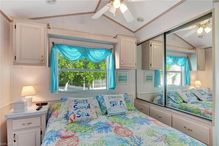 Bedroom with ceiling fan, lofted ceiling with beams, ornamental molding, and multiple windows