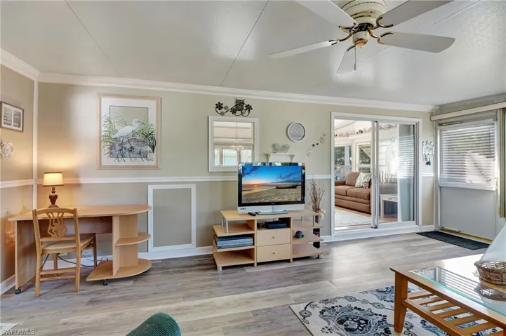 Living room with wood-type flooring, ornamental molding, and ceiling fan