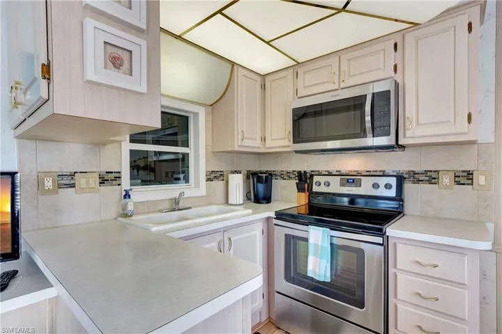 Kitchen featuring appliances with stainless steel finishes, kitchen peninsula, sink, and backsplash