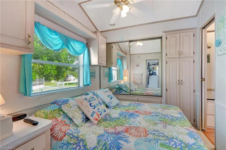 Bedroom featuring ceiling fan, ornamental molding, a closet, light carpeted flooring, and vaulted ceiling