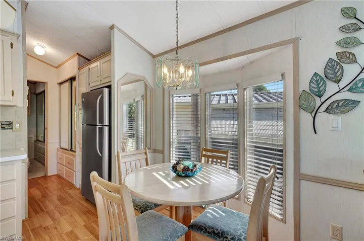 Dining area with lofted ceiling, light wood-type flooring, a notable chandelier, and a wealth of natural light
