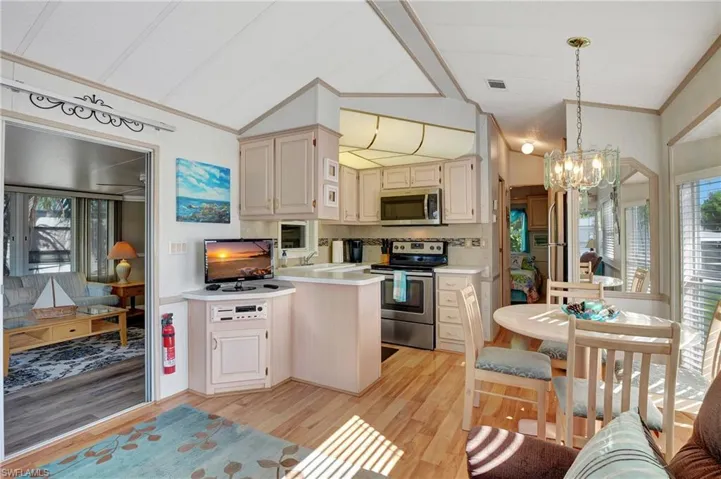 Kitchen featuring hanging light fixtures, light hardwood / wood-style flooring, appliances with stainless steel finishes, a notable chandelier, and decorative backsplash