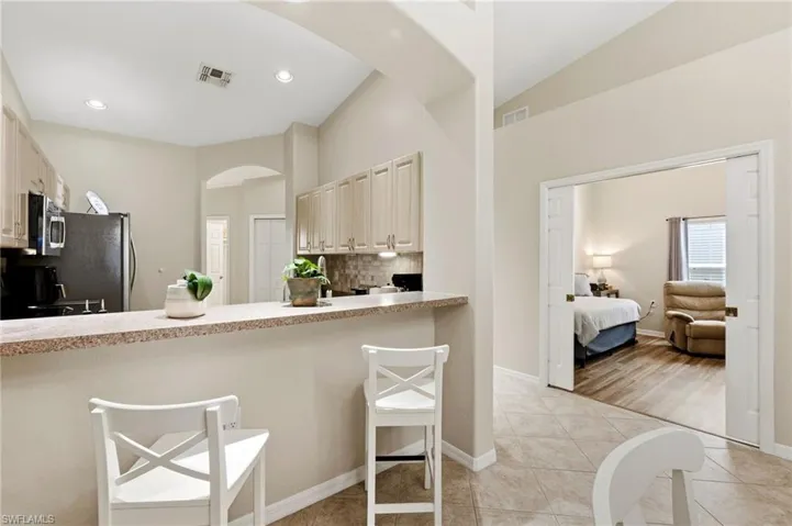 Kitchen with a breakfast bar area, backsplash, light countertops, vaulted ceiling, and arched walkways