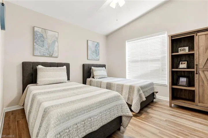 Bedroom with ceiling fan, lofted ceiling, and light wood-style floors