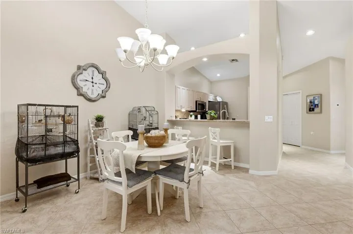 Dining space featuring high vaulted ceiling, arched walkways, a chandelier, light tile patterned flooring, and recessed lighting