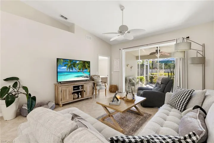 Living area with lofted ceiling, light tile patterned flooring, and ceiling fan