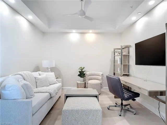 Office with ceiling fan, a raised ceiling, and wood-type flooring