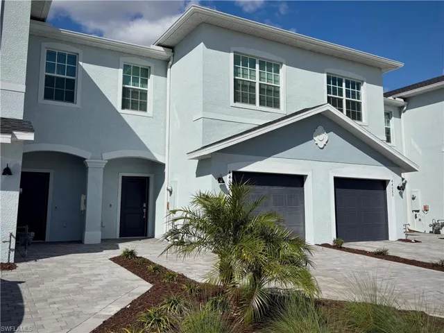Traditional home with a garage, stucco siding, and driveway