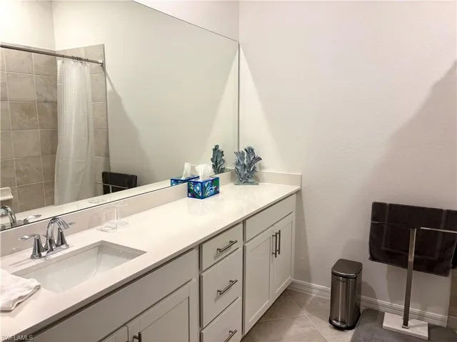 Bathroom with tiled shower, vanity, and light tile patterned floors