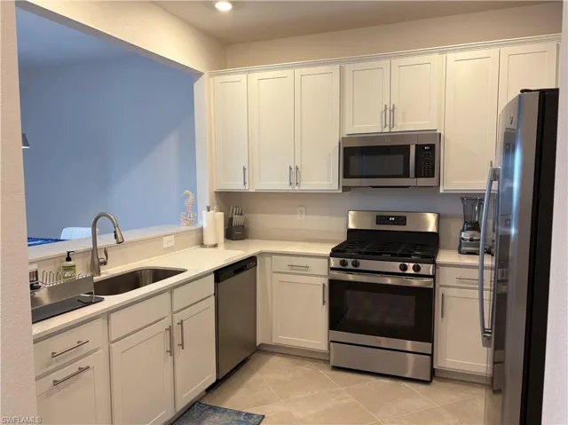 Kitchen with stainless steel appliances, white cabinetry, light stone countertops, light tile patterned floors, and recessed lighting
