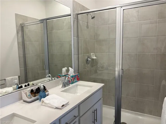 Bathroom with double vanity, a stall shower, and a textured wall