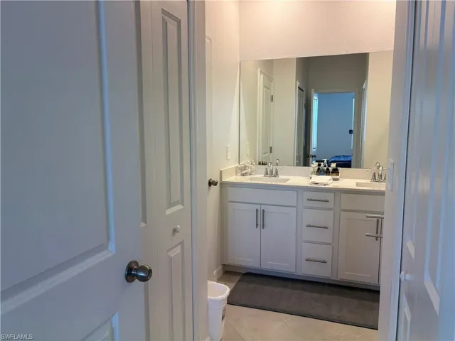 Bathroom featuring double vanity, light tile patterned flooring, and a textured wall