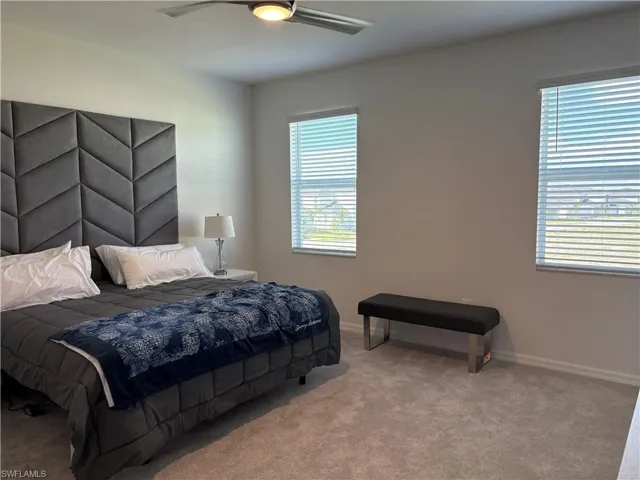 Carpeted bedroom featuring ceiling fan and baseboards