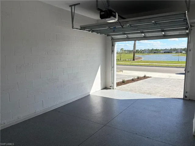 Garage with concrete block wall, a water view, and a garage door opener