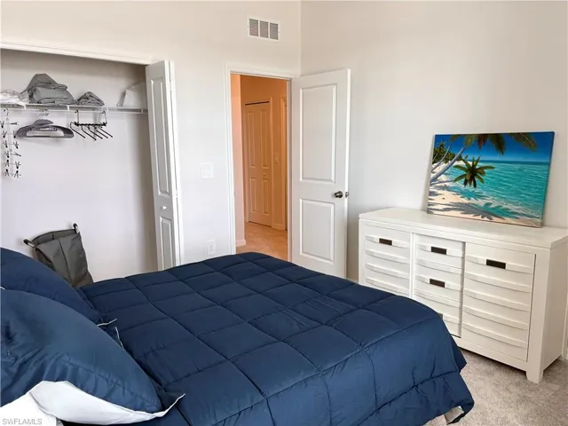 Bedroom with light colored carpet and a closet