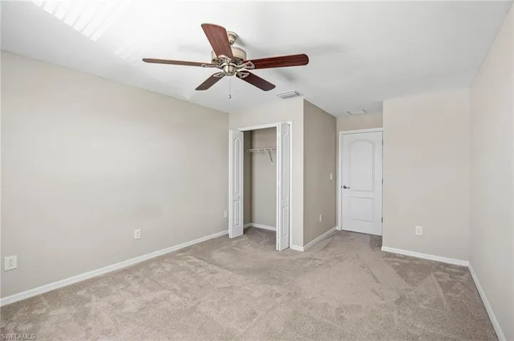 Unfurnished bedroom featuring light carpet, ceiling fan, and a closet