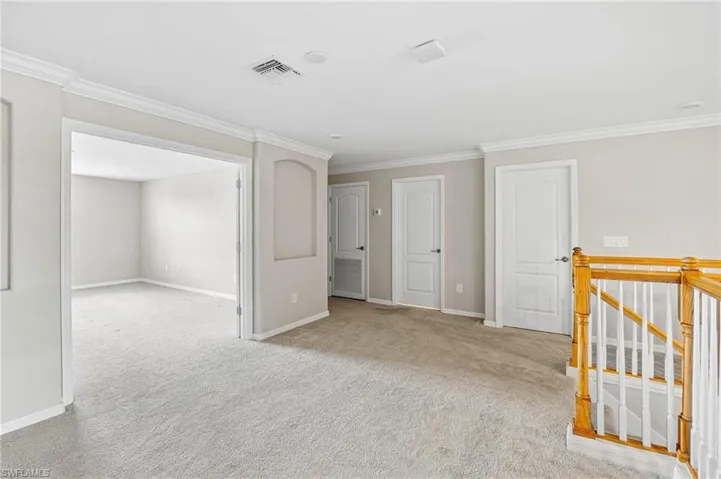 Carpeted spare room featuring ornamental molding