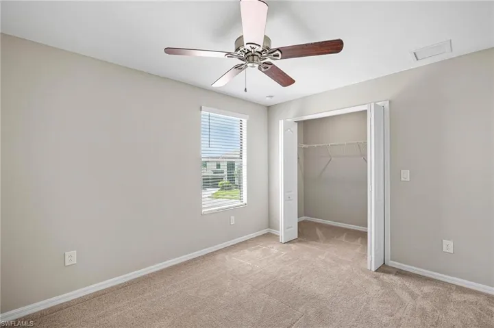 Unfurnished bedroom with light carpet, ceiling fan, and a closet