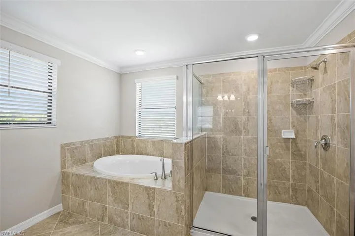 Bathroom with tile patterned flooring, separate shower and tub, and ornamental molding