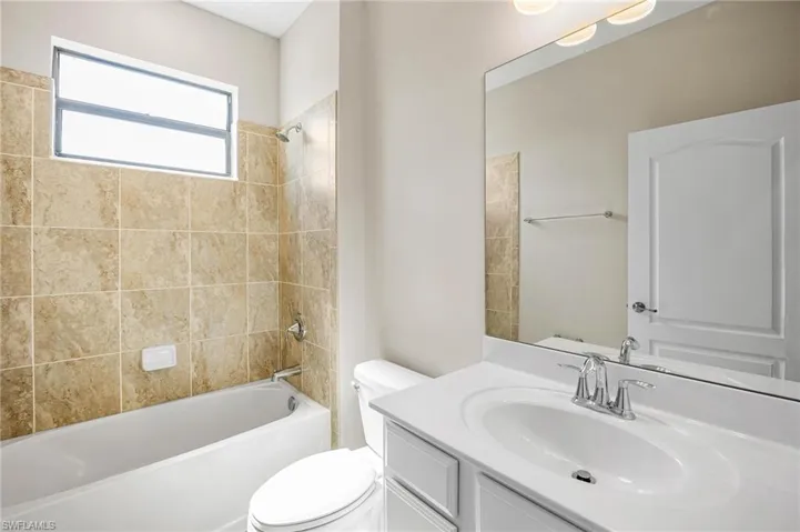 Full bathroom with tiled shower / bath, toilet, and vanity