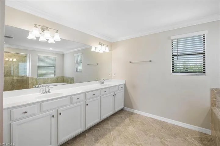 Bathroom with tile patterned flooring, vanity, ornamental molding, and shower with separate bathtub