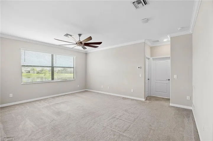 Spare room featuring light carpet, crown molding, and ceiling fan